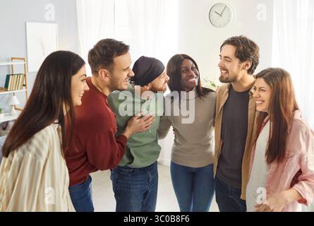 Happy people friends standing in circle and embracing, laughing and having fun Stock Photo