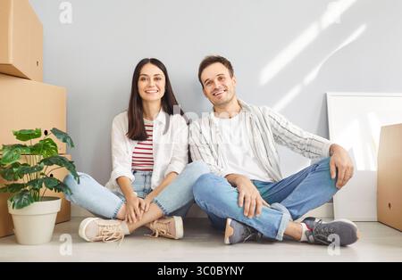 Happy young family, cheerful owners moving new flat, enter home, excited couple tenants sitting Stock Photo