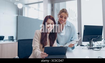 Two Professional Women Engaging in Collaboration Within a Contemporary Office Environment Stock Photo
