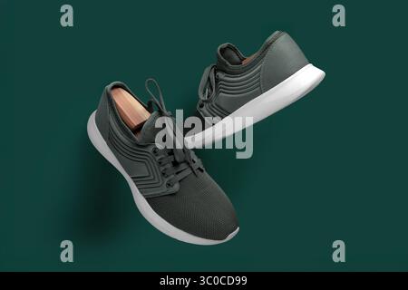 Stylish pair of green athletic sneakers with white soles, photographed from the top on a matching green background. The shoes feature mesh fabric and Stock Photo