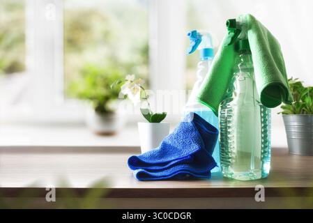 Cleaning products for dirt and dust in a transparent plastic bottle spray on wooden table with green and blue microfibre cloths with room in the backg Stock Photo