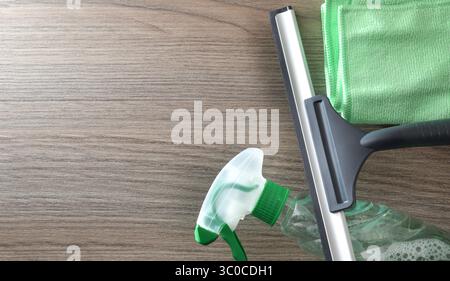 Window cleaner spatula, spray product and microfibre cloth isolated on wooden table. Top view. Stock Photo