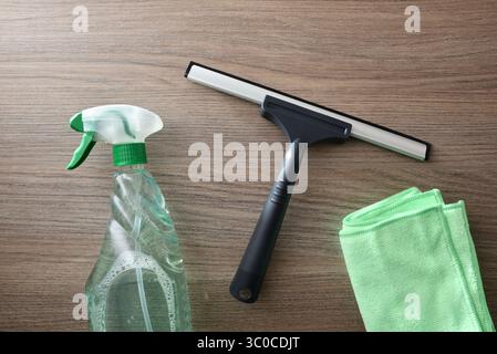 Window cleaner spatula, spray product and microfibre cloth on wooden table. Top view. Stock Photo