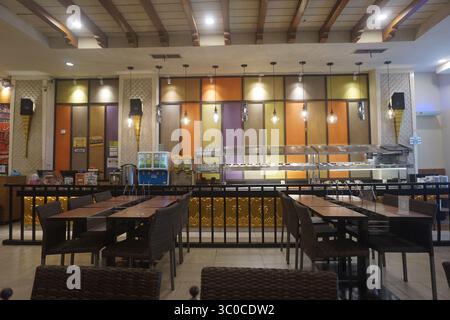 Interior view of a restaurant showcasing neatly arranged wooden tables and woven-style chairs at a mall in Depok Indonesia on 17 July 2025. Stock Photo