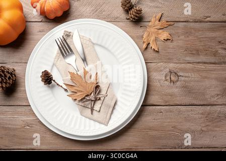 Thanksgiving Day or Halloween  place setting with pumpkins and dry maple leaves on wooden background, top view, copy space. Autumn holiday table setti Stock Photo