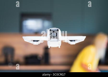 Modern white quadcopter drone with a video camera flying indoors. Concept of technology, video surveillance, delivery, and aerial photography. Stock Photo