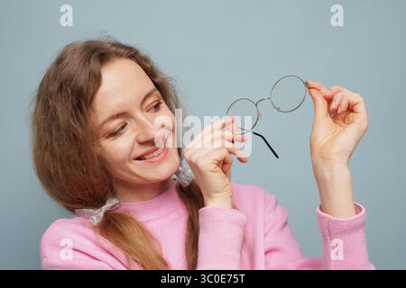 Happy woman looking at eyeglasses for vision correction, health, style, and modern lifestyle concept Stock Photo
