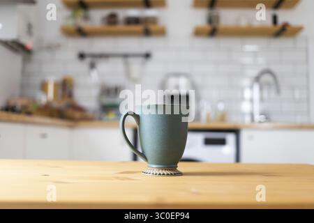 Green coffee cup on kitchen table blurred kitchen in background Stock Photo