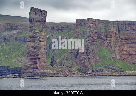 Impressive rock formations on the coast in contrast to overgrown green hill under cloudy sky, Old Men of Hoy, landmark, Hoy, Orkney Islands, Scotland Stock Photo