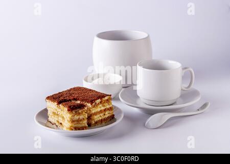 Coffee cup, a slice of tiramisu lies on a white plate on a white background Stock Photo