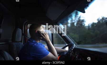 Man on phone while driving van during dusk, focused expression Stock Photo