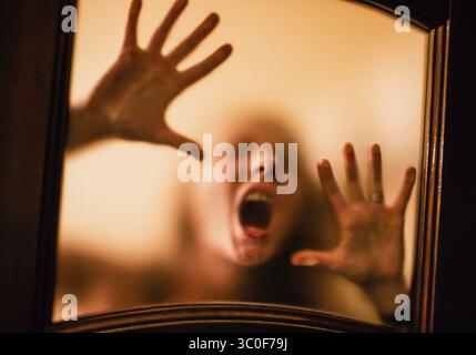Scary picture of hands behind glass, horror ghost woman behind door, Halloween concept Stock Photo