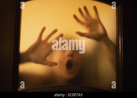Scary picture of hands behind glass, horror ghost woman behind door, Halloween concept Stock Photo