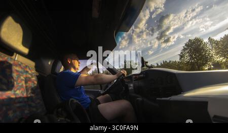 Man driving van with sunset lighting the road, serene scene Stock Photo