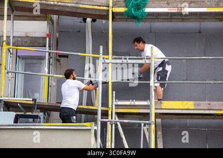 Construction workers insulates house facade Stock Photo