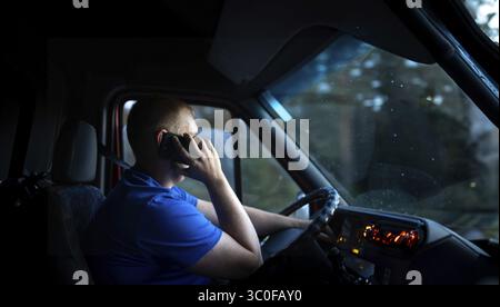 Man on phone while driving van at night, dimly lit interior Stock Photo