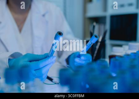 a female scientist is working in lab, a chemist tests liquid sample in science laboratory, she wears a lab coat when she works in laboratory, test tub Stock Photo