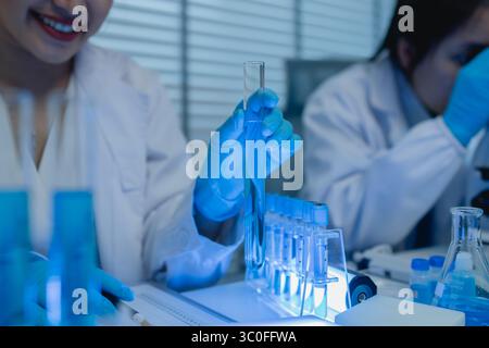 when in a lab, scientists wear lab coats, rubber gloves, and safety goggles, two chemists are testing chemicals in a liquid state Stock Photo