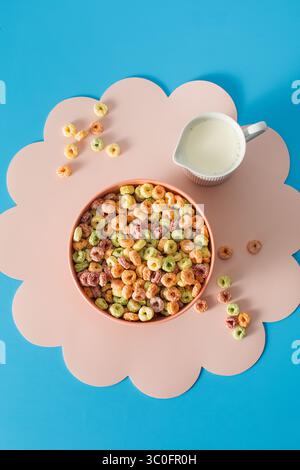 Colorful fruity cereal breakfast on pink mat with milk on blue background Stock Photo
