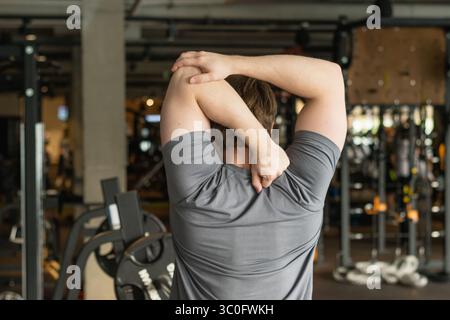 Athlete or caucasian young sporty man doing stretching back and arms at gym before workout. Training, wellness and athlete man workout. Preparation fo Stock Photo