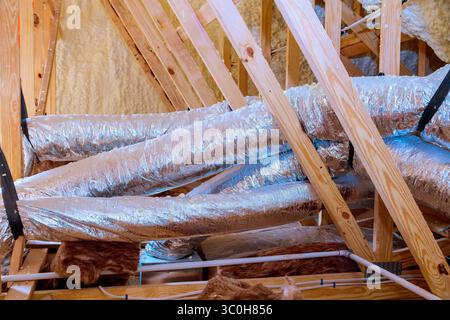 Installing insulated ductwork in residential attic during home renovation in new house Stock Photo