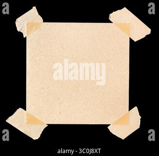 Square piece of blank brown paper affixed with four pieces of masking tape isolated on black background Stock Photo