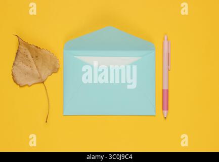 Envelope with a letter, pen, autumn leaf on a yellow background. Letter of love. Stock Photo