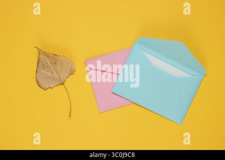 Envelope with letter, autumn leaf on yellow background. Letter of love. Top view Stock Photo