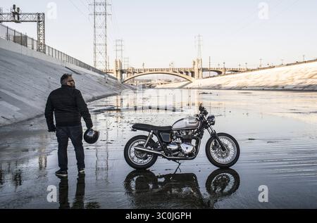 February 21, 2016 - Los Angeles, California, U.S - Man Standing with Motorcycle on Los Angeles River, Los Angeles, California, USA (Credit Image: © Novo Images/Glasshouse via ZUMA Wire) Stock Photo