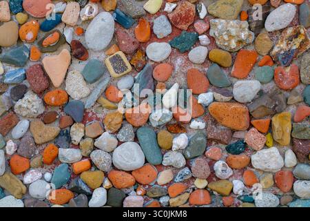 A colorful collection of smooth stones and pebbles lies on a natural surface, illuminated by sunlight, displaying unique textures and an eye-catching Stock Photo