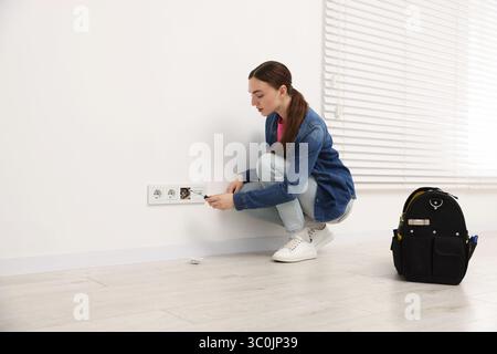 Woman with screwdriver installing new socket at home Stock Photo