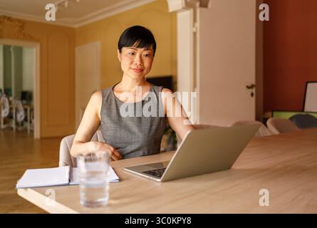 Portrait of confident female entrepreneur reading e-mails over laptop while working at desk in office Stock Photo