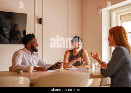 Happy group of coworkers working together on project in board room using computers and documents Stock Photo