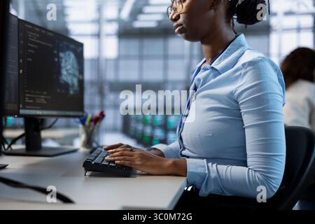 AI data center technician writing disaster recovery plans ensuring minimal downtime. IT professional in server farm uses analytics to monitor performance and predict needed equipment upgrades Stock Photo