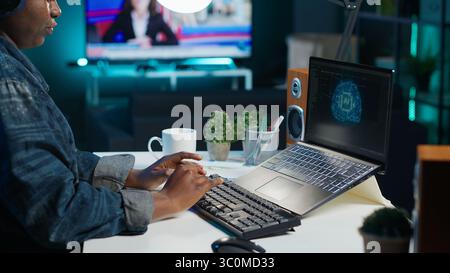 Data scientist using laptop, updating artificial intelligence machine learning algorithms, writing code scripts. Teleworking IT specialist in apartment office uses programming to upgrade AI, camera A Stock Photo
