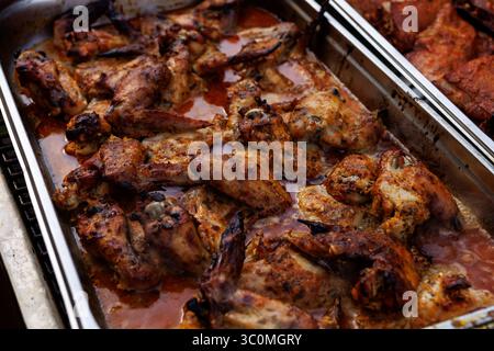 Metal tray filled with roasted chicken wings in marinade. Brown crispy texture and oily surface. Stock Photo
