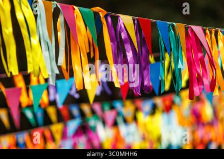 Bright multi-colored streamers and triangular flags strung outdoors. Decoration for celebration or event. Stock Photo