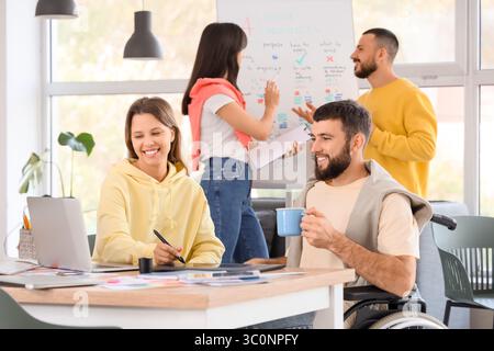 Male designer with coffee cup and his colleague working at office Stock Photo