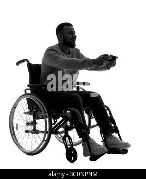 Silhouette of young man in wheelchair playing video game on white background Stock Photo