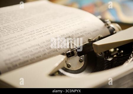Close up showing vintage typewriter with typed page emerging, focusing on mechanical keys and textured paper, capturing detail of classic writing process in retro office setting Stock Photo