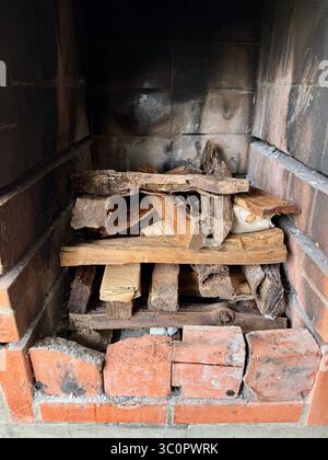 Stacked firewood and kindling prepared in a brick barbecue pit for lighting. Stock Photo