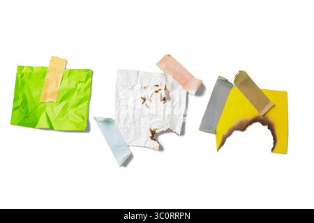Burnt white and yellow paper with green crumpled paper on adhesive masking tape isolated over a white background. Copy space Stock Photo