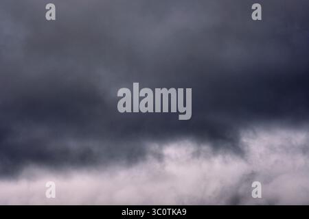 Thick, dark clouds dominate the sky, signaling an impending rainstorm. The atmosphere feels heavy and charged with energy. Stock Photo