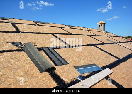 Roofing construction with oriented strand board (OSB) and bitumen waterproofing before laying asphalt shingles, roof repair Stock Photo
