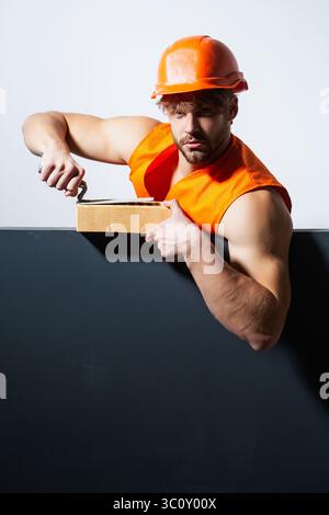 Builder with bricks, funny sale on construction site. Funny builder man with helmet doing brickwork. Builder posing with bricks blocks. Bricklayer Stock Photo