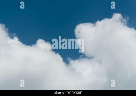 Background of a deep blue summer sky and fluffy white clouds Stock Photo