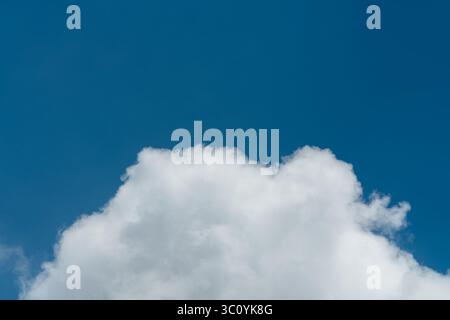 Background of a deep blue summer sky and fluffy white clouds Stock Photo