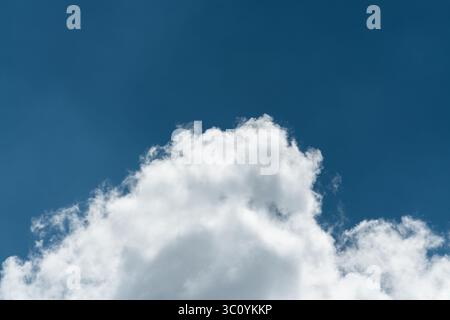 Background of a deep blue summer sky and fluffy white clouds Stock Photo