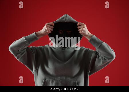 Anonymity. Woman wearing mask on red background Stock Photo