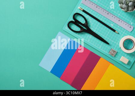Workspace for paper crafts. Turquoise cutting mat, colored paper, pencils, tape, ruler, scissors. Space for your text. Stock Photo